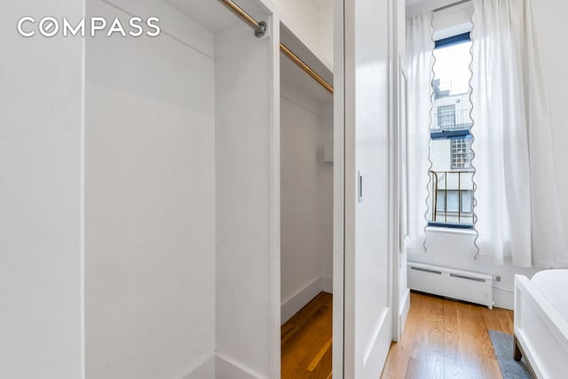 spacious closet with light wood-type flooring and a baseboard radiator