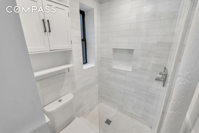 bathroom with a tile shower and toilet
