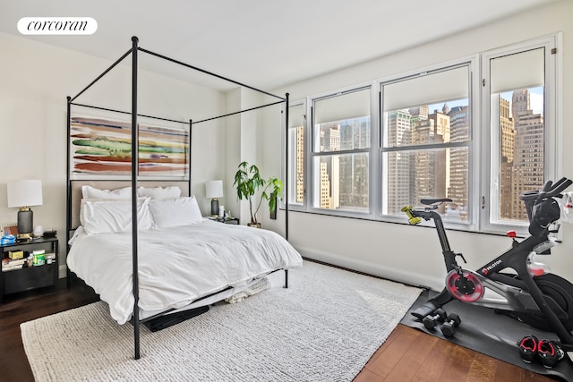 bedroom featuring baseboards, visible vents, a city view, and wood finished floors