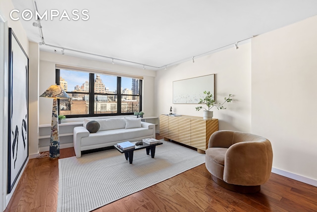 living area featuring baseboards, a view of city, wood finished floors, and track lighting