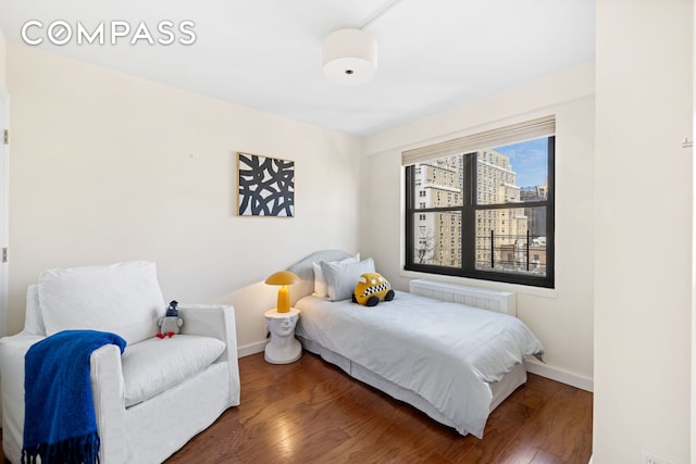 bedroom featuring radiator heating unit, baseboards, and wood finished floors