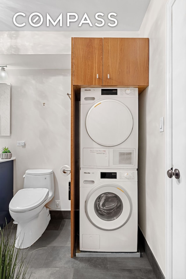 washroom featuring stacked washer and dryer, laundry area, and baseboards