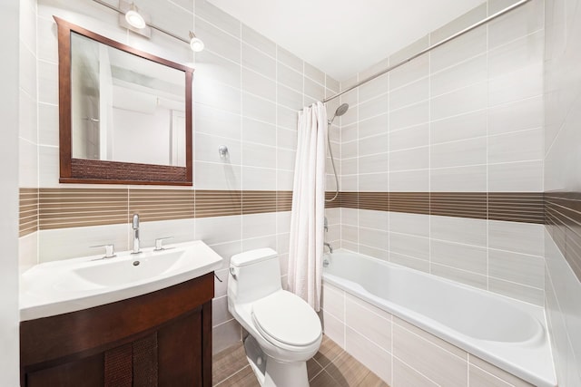 full bathroom featuring toilet, tiled shower / bath combo, vanity, and tile walls