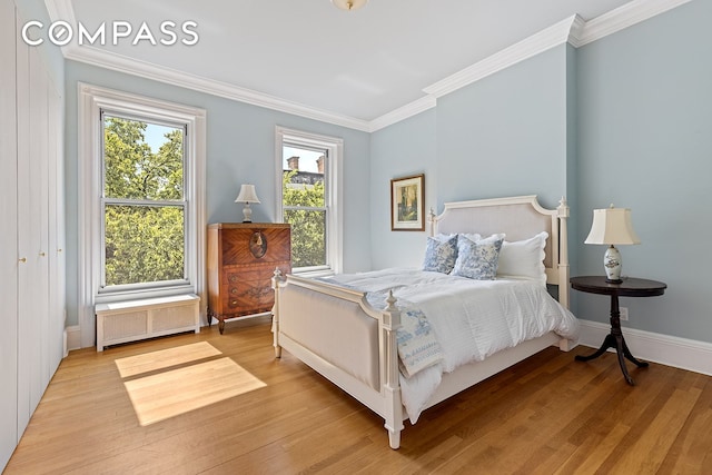 bedroom featuring radiator, light wood-style floors, baseboards, and crown molding