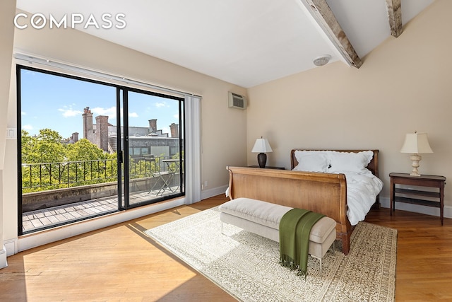 bedroom with a view of city, beam ceiling, wood finished floors, access to outside, and baseboards