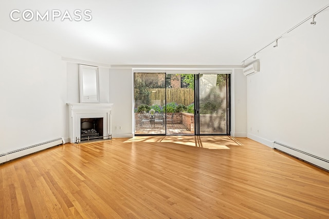 unfurnished living room with light wood-style floors, a baseboard radiator, a fireplace, and a wall mounted air conditioner