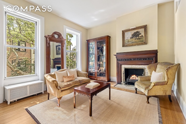 sitting room featuring baseboards, a fireplace, radiator heating unit, and wood finished floors