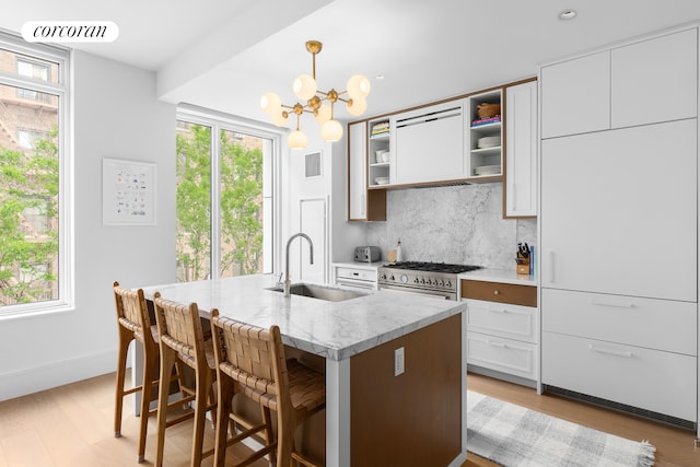 kitchen with a notable chandelier, a sink, visible vents, high end stainless steel range, and backsplash