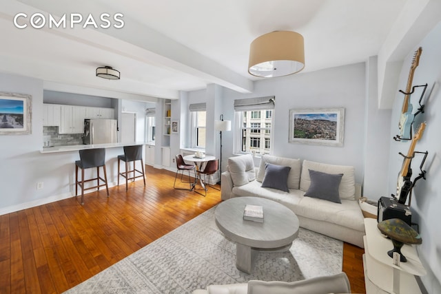 living room with light wood finished floors, baseboards, and beam ceiling