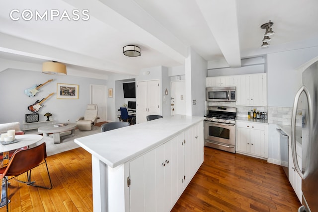 kitchen featuring light countertops, appliances with stainless steel finishes, white cabinetry, and tasteful backsplash