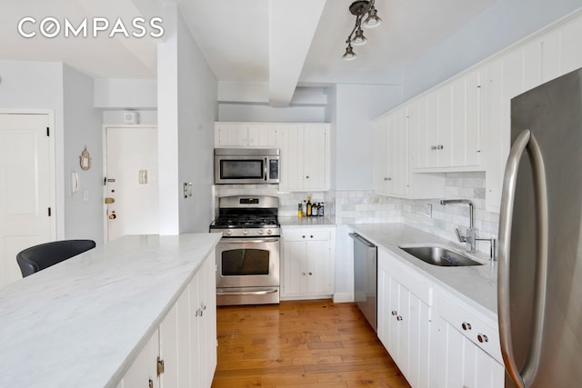 kitchen featuring appliances with stainless steel finishes, white cabinets, a sink, and backsplash