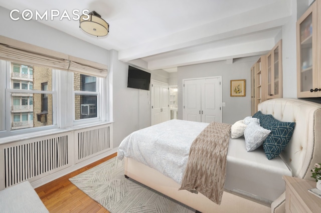 bedroom featuring beamed ceiling and wood finished floors