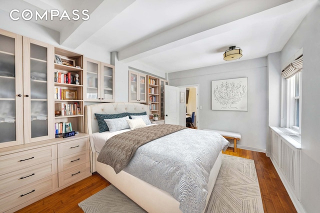 bedroom featuring radiator heating unit, baseboards, dark wood-style flooring, and beamed ceiling