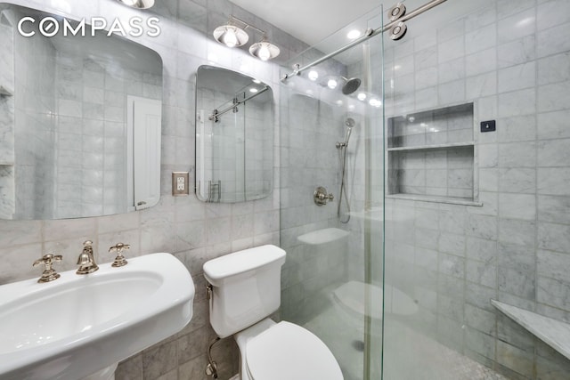 full bathroom with toilet, a sink, tile walls, a shower stall, and decorative backsplash