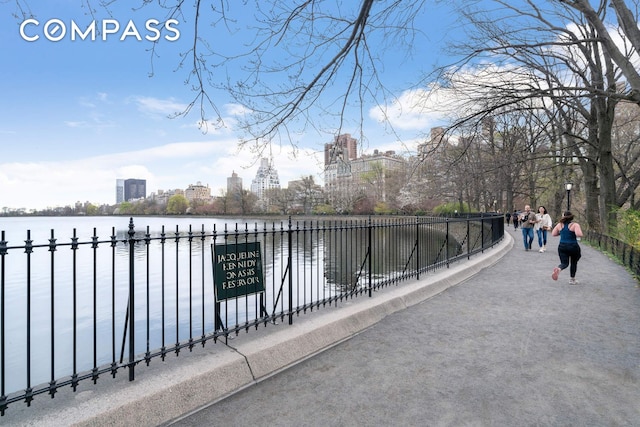 exterior space with a water view, fence, and a city view