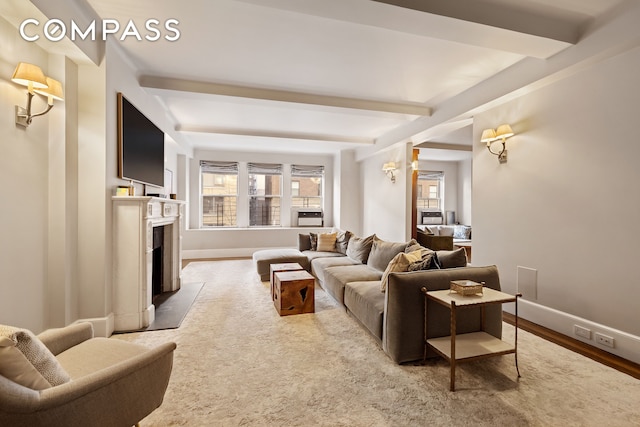 living room featuring beam ceiling, a fireplace with flush hearth, baseboards, and wood finished floors