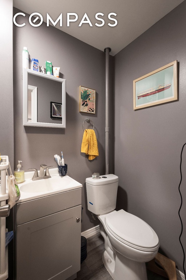 bathroom featuring baseboards, vanity, toilet, and wood finished floors