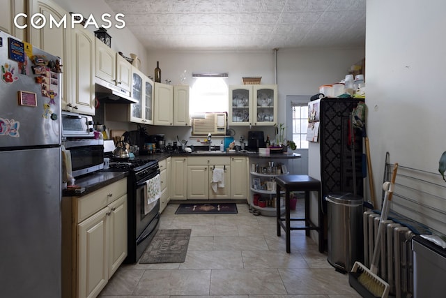 kitchen featuring stainless steel appliances, dark countertops, glass insert cabinets, and radiator heating unit