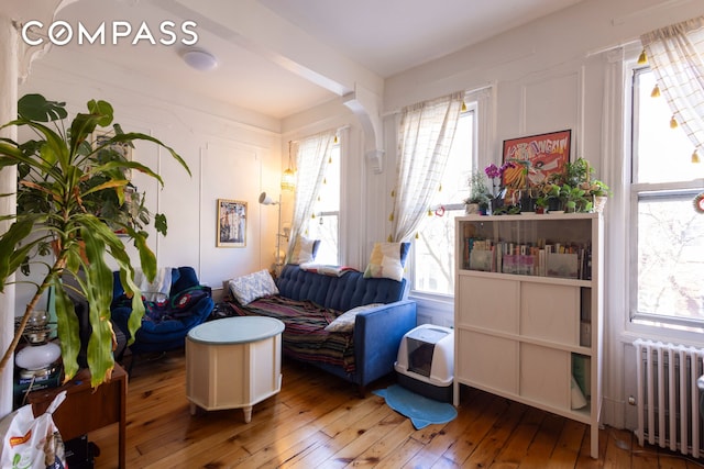 sitting room with radiator, a healthy amount of sunlight, and wood-type flooring