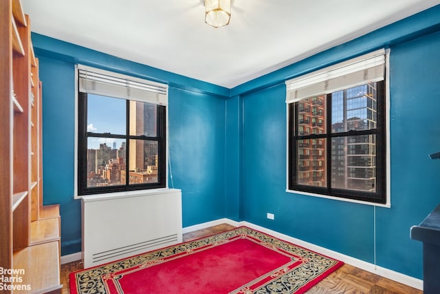 spare room featuring baseboards, a city view, and radiator