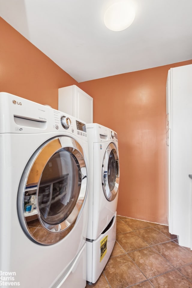 clothes washing area with washing machine and dryer and cabinet space