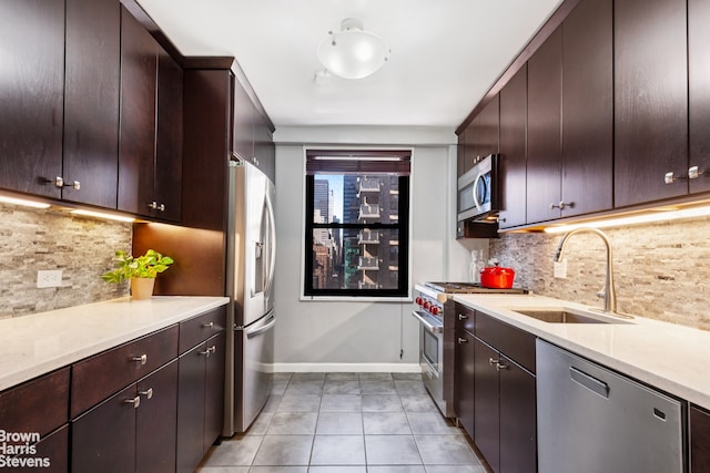 kitchen featuring light tile patterned floors, baseboards, appliances with stainless steel finishes, light countertops, and a sink