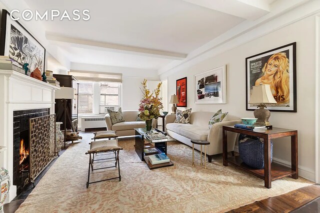 living area with beam ceiling, radiator, and a fireplace with flush hearth