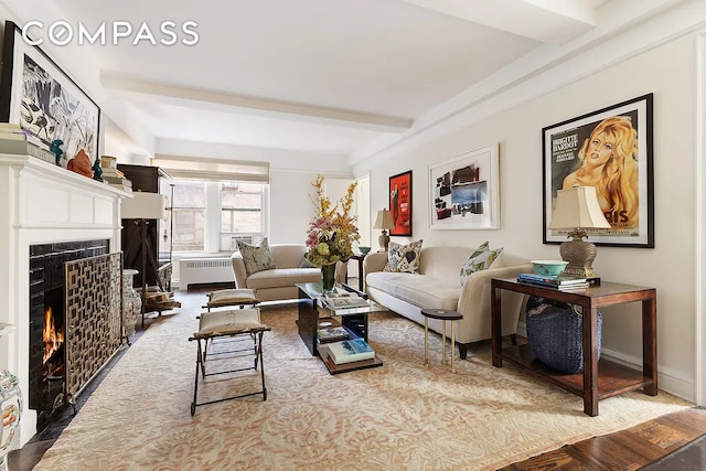 living area featuring beam ceiling, a fireplace with flush hearth, and radiator heating unit