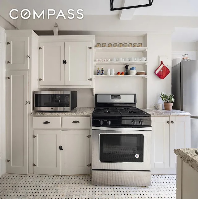 kitchen with open shelves, stainless steel appliances, light stone countertops, and white cabinets