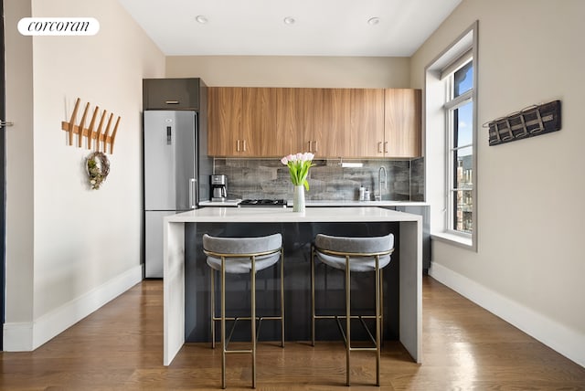 kitchen with a wealth of natural light, light countertops, a breakfast bar, and freestanding refrigerator