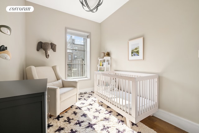 bedroom with a crib, baseboards, and wood finished floors