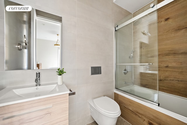 full bath featuring enclosed tub / shower combo, toilet, vanity, and tile walls