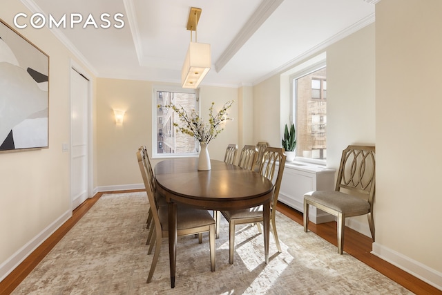 dining room with crown molding, wood finished floors, baseboards, and a tray ceiling