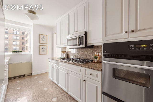 kitchen with stainless steel appliances, granite finish floor, white cabinetry, baseboards, and decorative backsplash