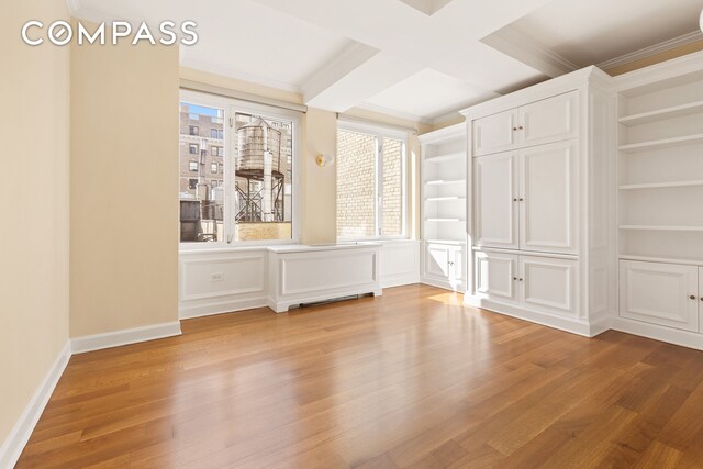 interior space featuring built in shelves, ornamental molding, coffered ceiling, and wood finished floors