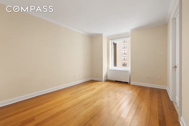 unfurnished room featuring ornamental molding, light wood finished floors, and baseboards