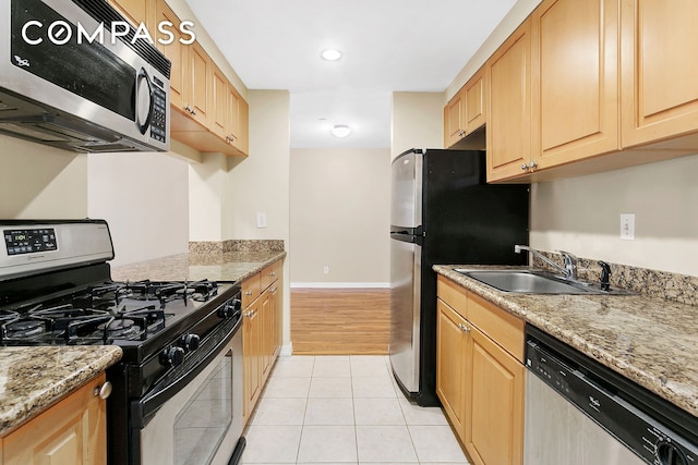 kitchen with light tile patterned floors, light brown cabinets, appliances with stainless steel finishes, and a sink