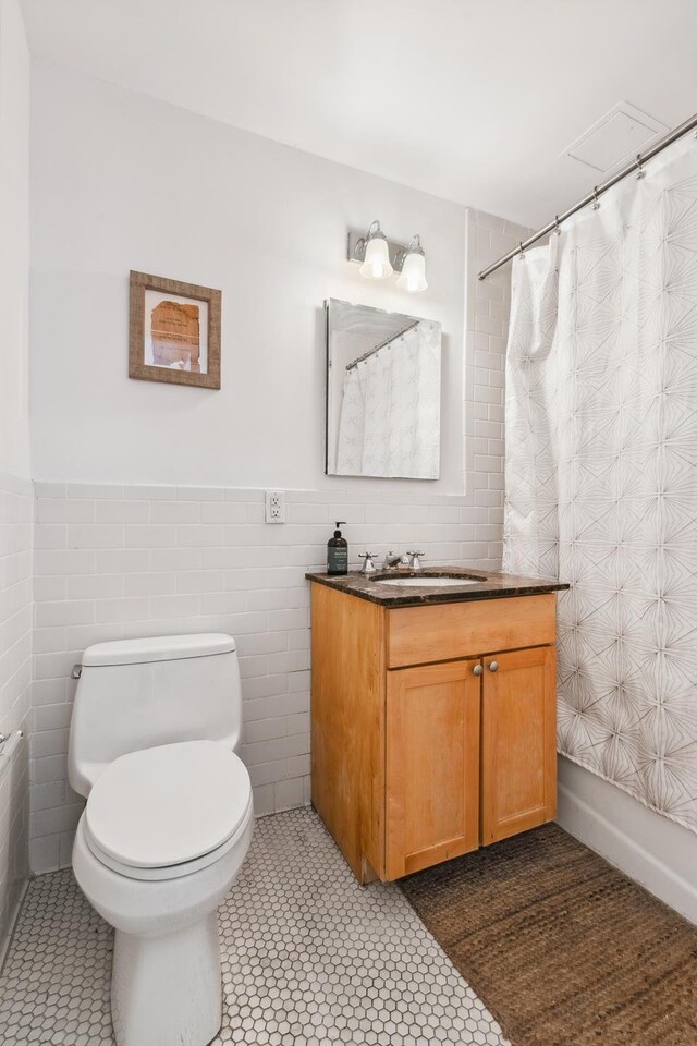 69 E 130th St Unit 1C, New York City, NY 10037 - full bath featuring vanity, wainscoting, toilet, tile walls, and a shower with shower curtain