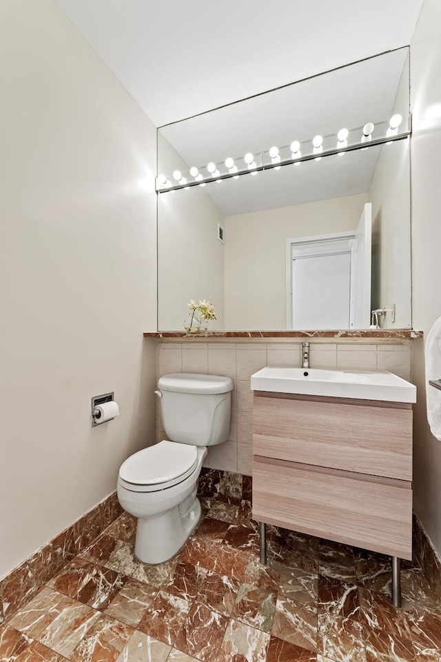 half bath featuring marble finish floor, vanity, and toilet