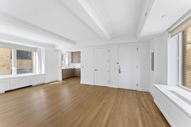 unfurnished bedroom featuring a sink, baseboards, light wood-style floors, electric panel, and beam ceiling