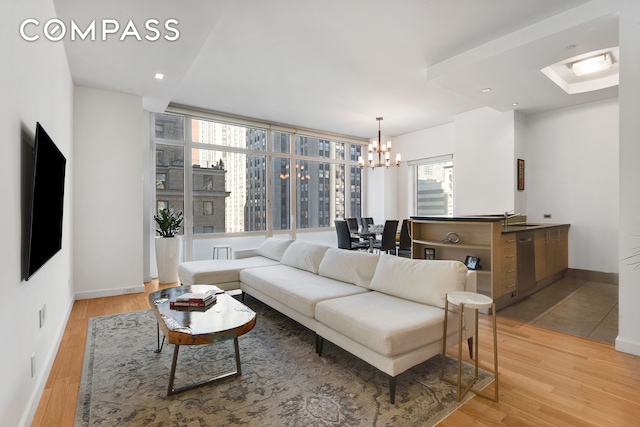 living area featuring light wood-style floors, baseboards, and a notable chandelier