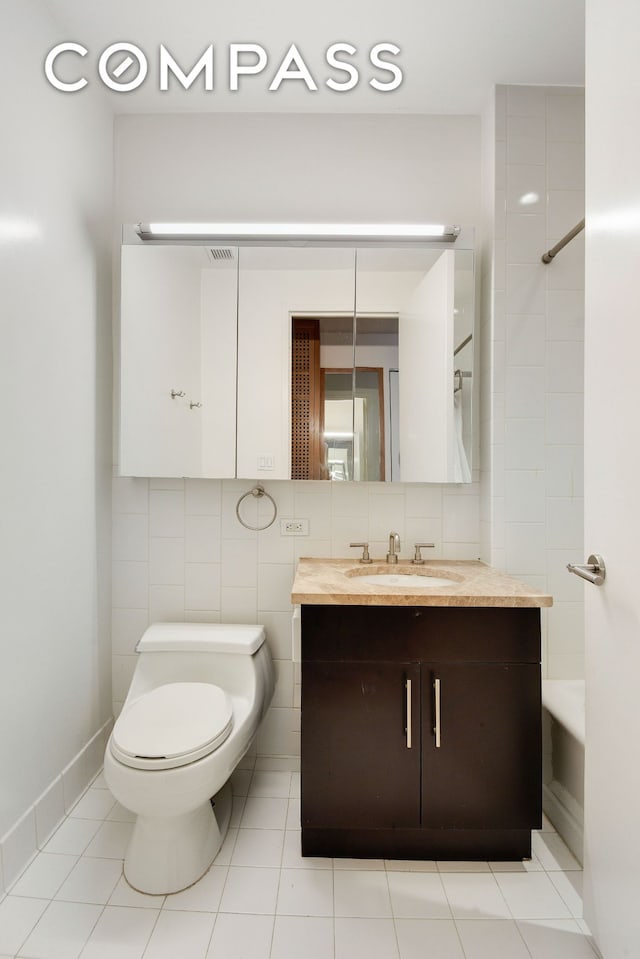 bathroom featuring toilet, vanity, tile walls, backsplash, and tile patterned floors