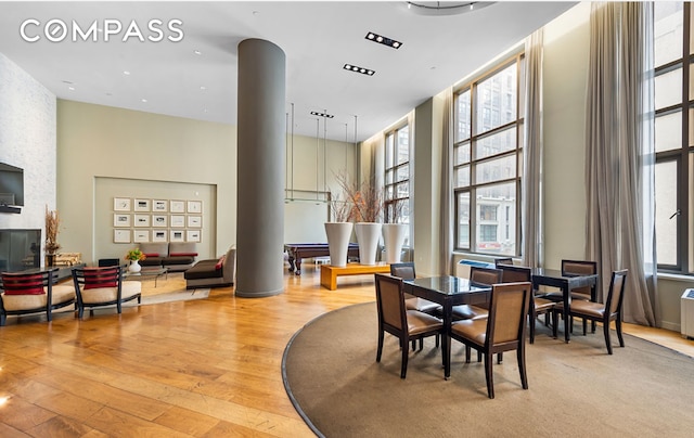 dining space featuring light wood-style floors, decorative columns, and a healthy amount of sunlight