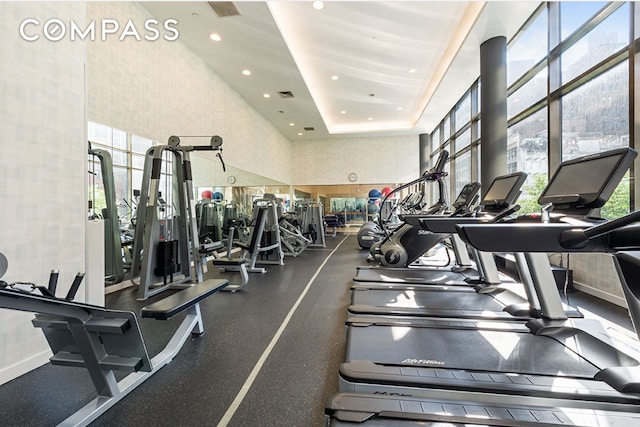 workout area with recessed lighting, visible vents, a towering ceiling, and a tray ceiling