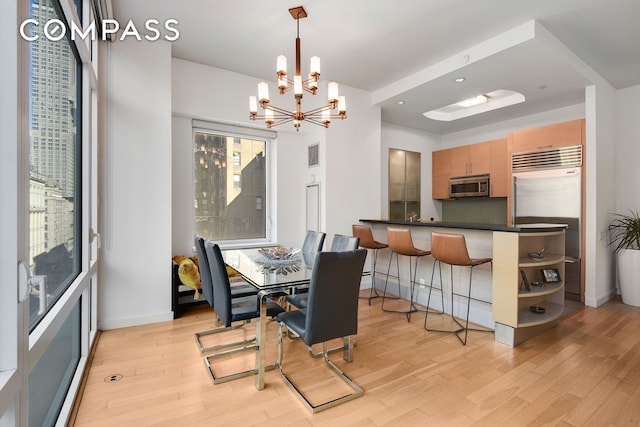 dining space with an inviting chandelier, light wood-style flooring, and baseboards