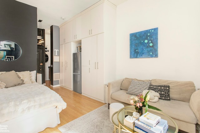 bedroom with light wood finished floors and freestanding refrigerator