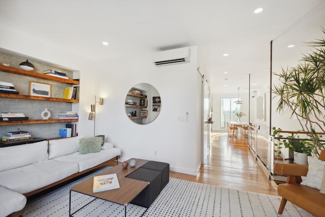 living area with baseboards, built in features, a wall mounted air conditioner, light wood-type flooring, and recessed lighting