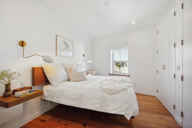 bedroom with baseboards, recessed lighting, and light wood-style floors