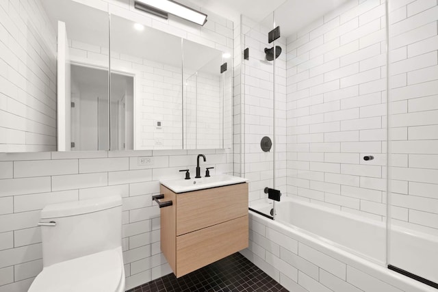 bathroom with tile walls, toilet, tiled shower / bath, vanity, and backsplash