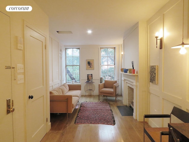 living area with a fireplace with flush hearth, visible vents, a decorative wall, and light wood-style flooring